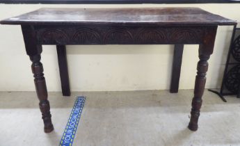 An 18thC oak side table with a planked top and thumb moulded edge, over a lunette carved frieze,