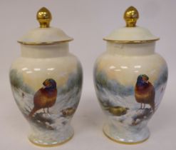 A pair of Coalport bone china vases of baluster form, the covers having knop finials, decorated by