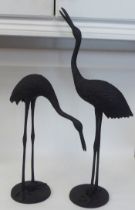 Two modern enamelled black, cast metal models, cranes, on circular plinths  21" & 30"h