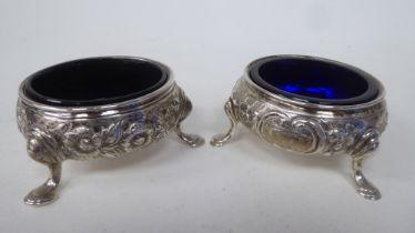 A pair of late 18thC silver salt cellars of shallow bowl design with embossed floral ornament, on