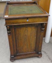 A late Victorian rosewood Davenport with a hinged top and a panelled flank cupboard, on a plinth and