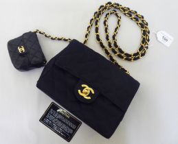 A quilted black shoulder bag with a black leather, attached purse