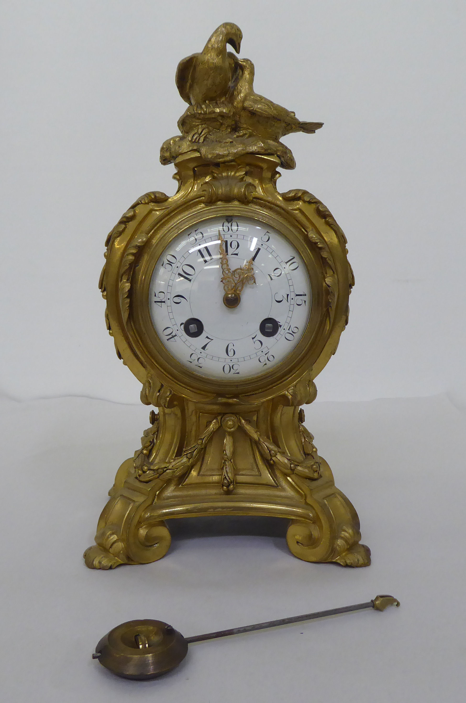 A reproduction of a 19thC gilt metal cased mantel clock of balloon design, surmounted by a pair of