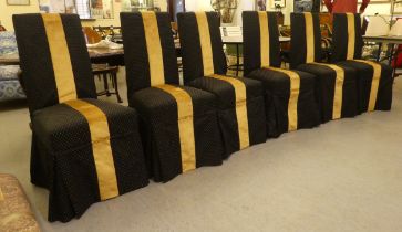 A set of six black and gold fabric covered dining chairs, raised on stained beech legs