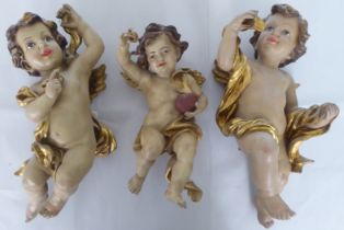 Three overpainted composition cherubic figures  largest 14"h