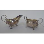 A silver sauce boat with a scrolled handle and a silver, oval twin handled sugar basin  mixed marks