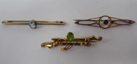 Three late Victorian 9ct gold and yellow metal scarf brooches, one set with a peridot
