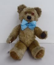 A mid 20thC mohair covered Teddy bear with mobile limbs, a blue ribbon and growler  20"h