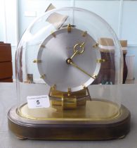 A Kundo Electromagnetic mantel clock; the exposed movement faced by a baton dial  9''h under a glass