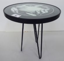 A Fornasetti style wrought metal occasional table stool with a glass top  15"h  12"dia