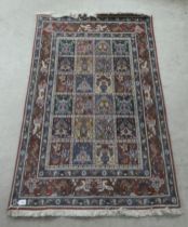 A Persian rug, decorated with repeating box formation and bordered by stylised floral designs, on