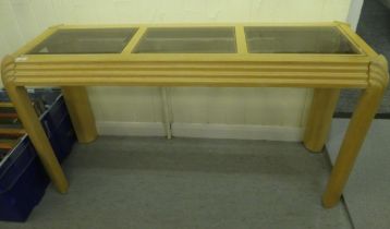 A modern stained beech hall table with a panelled glass top, raised on chamfered legs  28"h  51"w