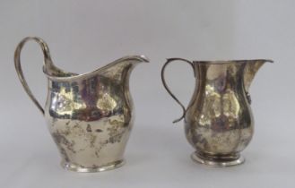 Two silver milk jugs, each with an ear shaped handle  mixed marks