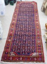 A Persian runner, decorated with geometric motifs, on a red and blue ground  140" x 43"