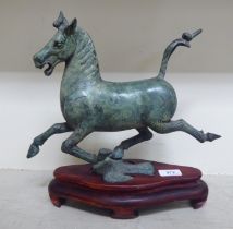 A Chinese patinated bronze model, a galloping horse, on a wooden plinth  13"h