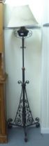 A late Victorian wrought iron, height adjustable, oil standard lamp, raised on scrolled legs  62"h