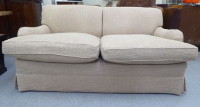 A modern settee with a level back and enclosed arms, upholstered in biscuit coloured fabric with a