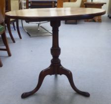 A Georgian style mahogany tip-top pedestal table, over a vase turned column, raised on a tripod