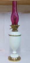 An early 20thC pale green china and brass mounted table pedestal lamp with a cranberry coloured