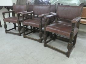 A set of six 1920s Old English Gothic style, carved oak framed open armchairs, stud upholstered in