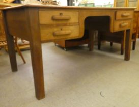 A 1930s oak desk with four drawers, raised on block legs  30"h  62"w