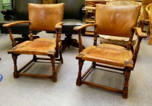 A pair of 1930w oak framed chairs with brown hide upholstered backs and seats, raised on block legs