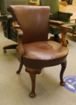 An early 20thC mahogany framed desk chair with a brown hide upholstered back and seat, raised on