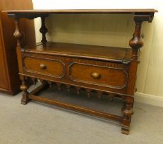 A 1930s oak monks bench with a carved lift and slide back, over a hinged seat, raised on splayed