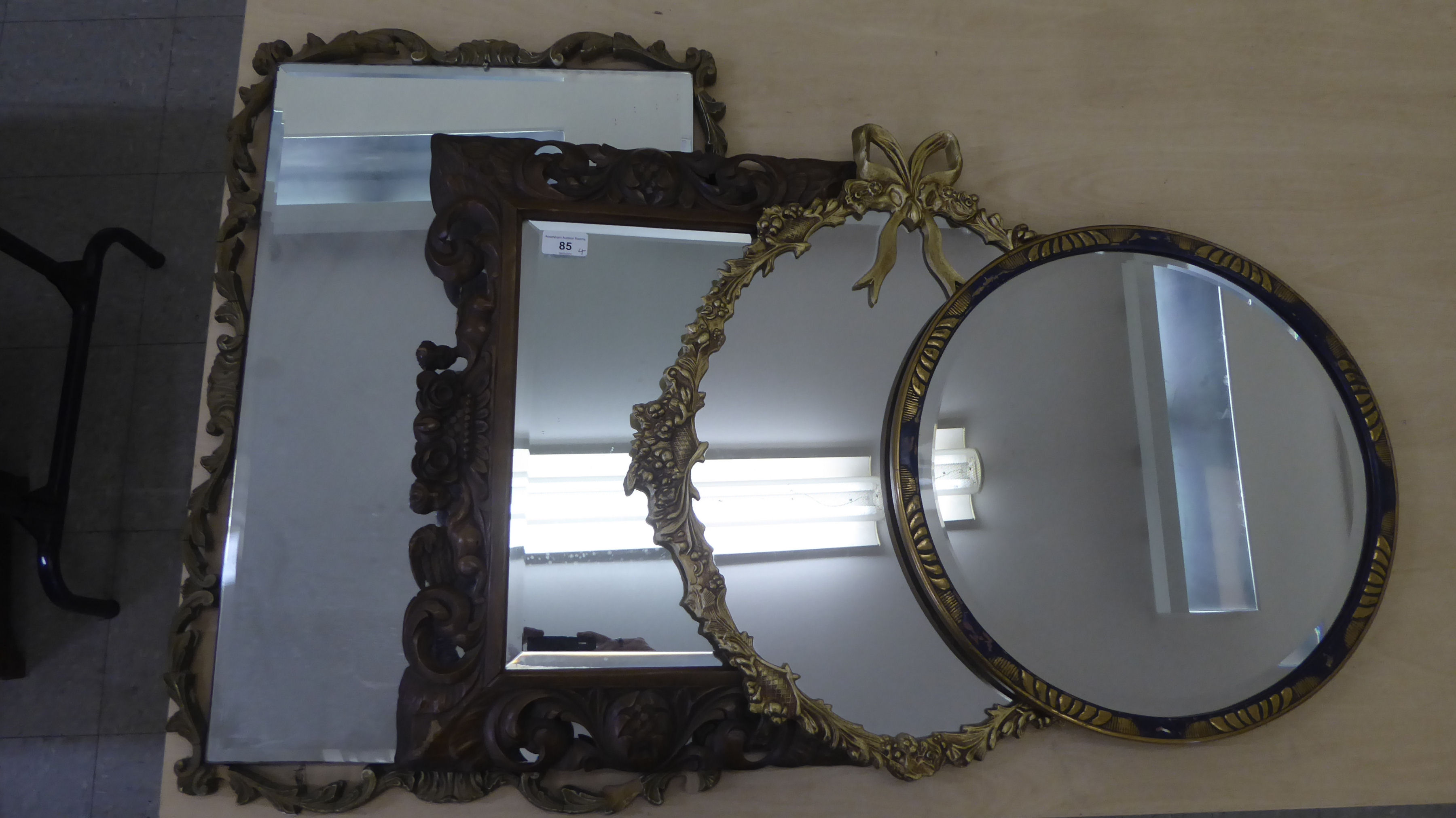 Four dissimilar mirrors: to include one with a bevelled edge, set in a carved and stained hardwood