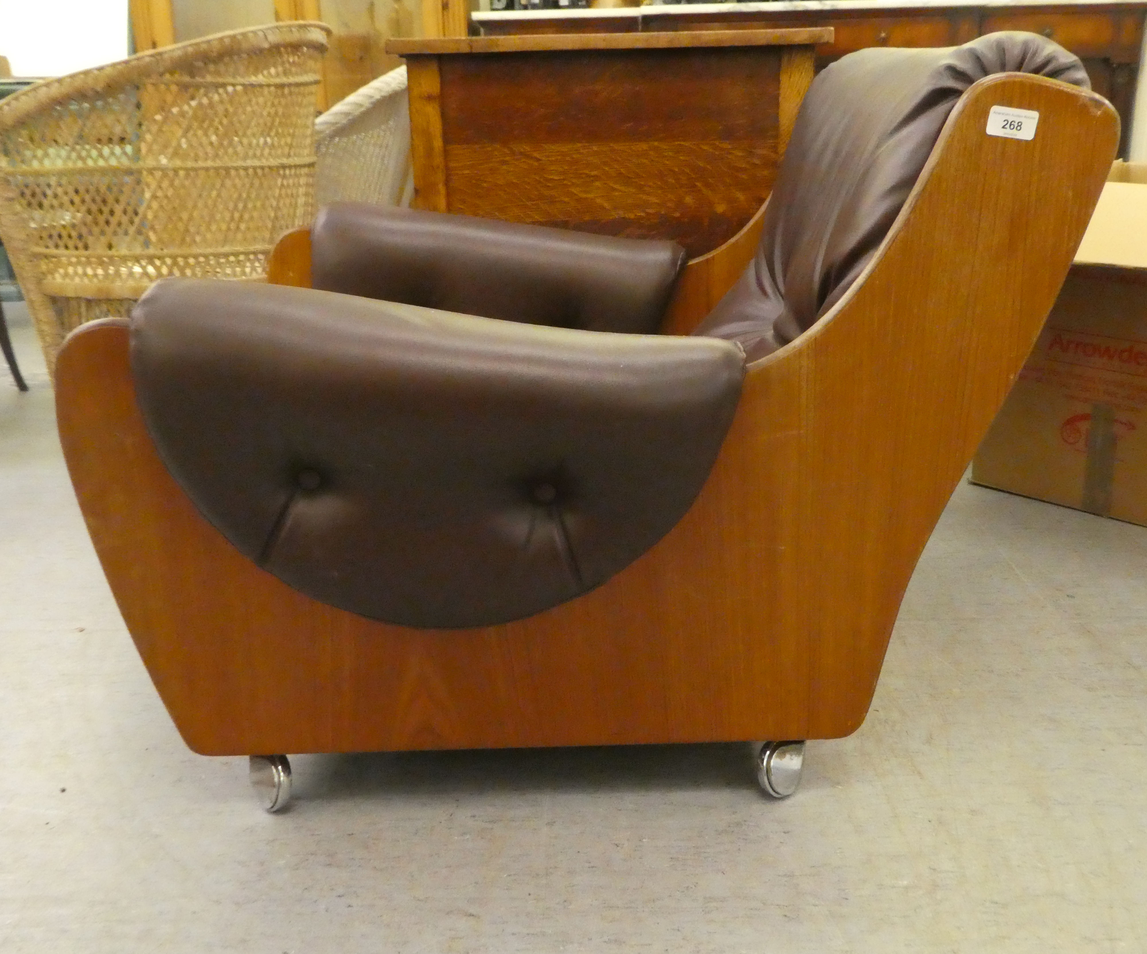 A 1960/70s G-Plan teak framed easy chair with a faux brown hide upholstered back and seat