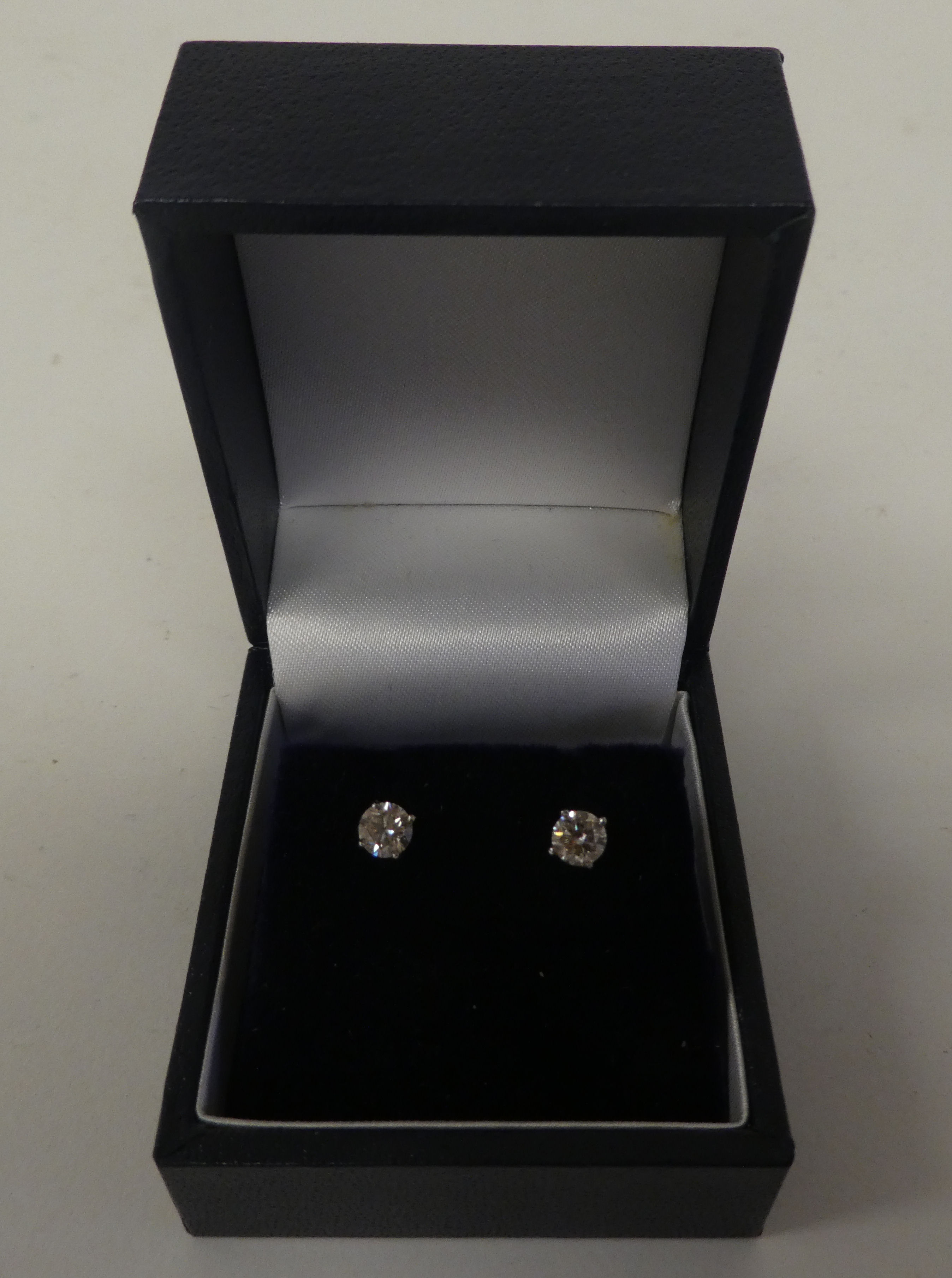 A pair of 14ct white gold, claw set, single stone diamond earrings