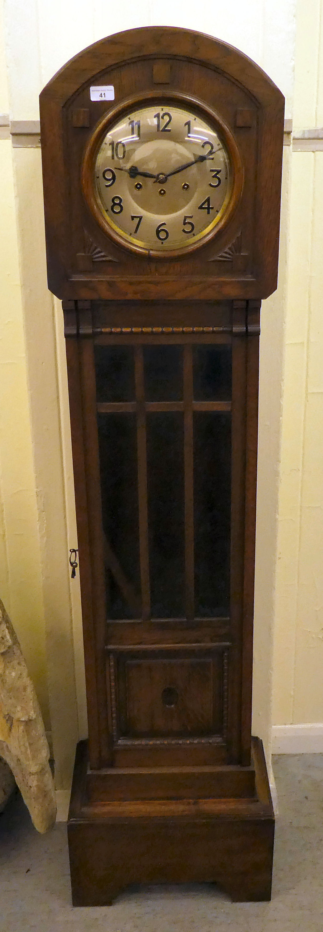 A mid 20thC oak longcase clock with a pointed arch top, over a convex circular window and a bevelled