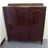 A mid 20thC mahogany breakfront cabinet with three panelled doors, raised on cabriole legs  52"h
