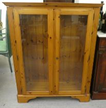 A modern stained pine bookcase with two glazed doors, on a bracket plinth  48"h  39"w