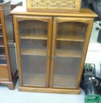 An Ercol mid tone elm cabinet with two glazed doors, on a plinth  45"h  37"w