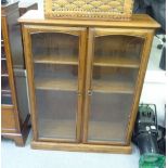 An Ercol mid tone elm cabinet with two glazed doors, on a plinth  45"h  37"w