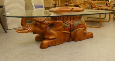 A modern teak framed coffee table, the base fashioned as an elephant with a glass top  14"h  54"L