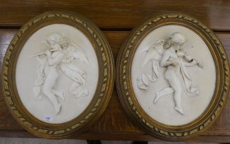 Two modern composition plaques, decorated in relief with cherubic figures  16"h  13"dia