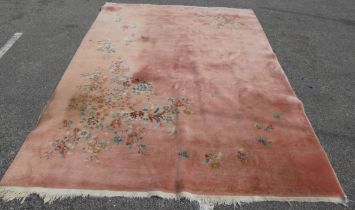 A Chinese washed woollen rug, decorated with flora, on a salmon pink coloured ground  100" x 148"