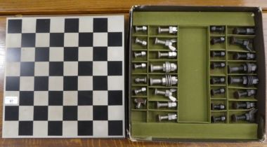 A novelty chess set, the metal board  14"sq the pieces fashioned out of nuts and bolts