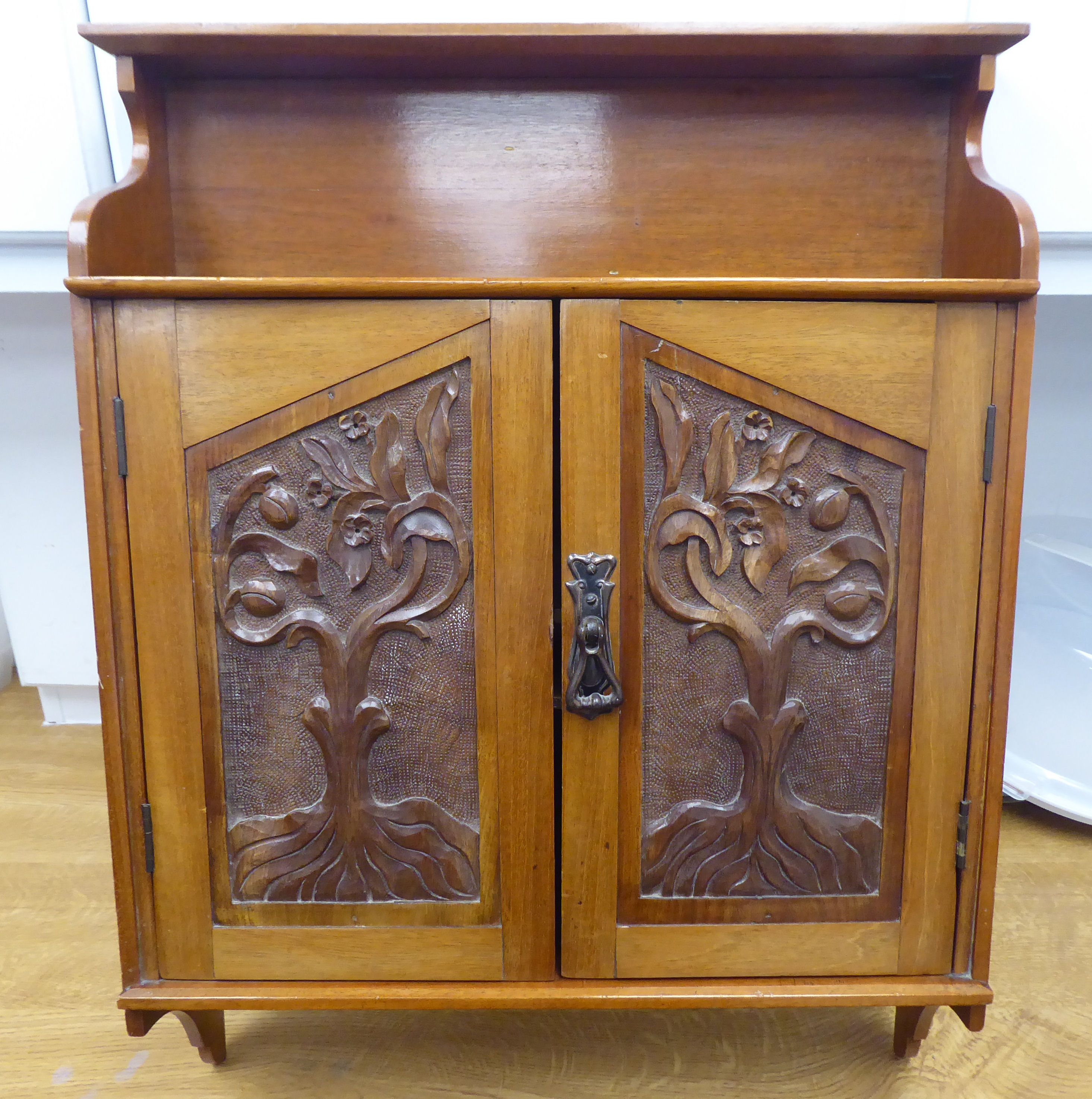 An early 20thC mahogany hanging cupboard with a display shelf, over a pair of doors, featuring Art