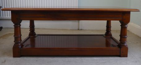 A modern Cherrywood two tier coffee table, raised on turned and block legs  16"h  42"w