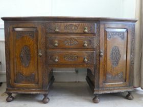 A 1930s oak bowfront sideboard with a central bank of three drawers, flanked by a pair of fret