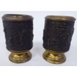 A pair of lacquered brass and tinplate vesta holders, fashioned with embossed scenes of cherubs in