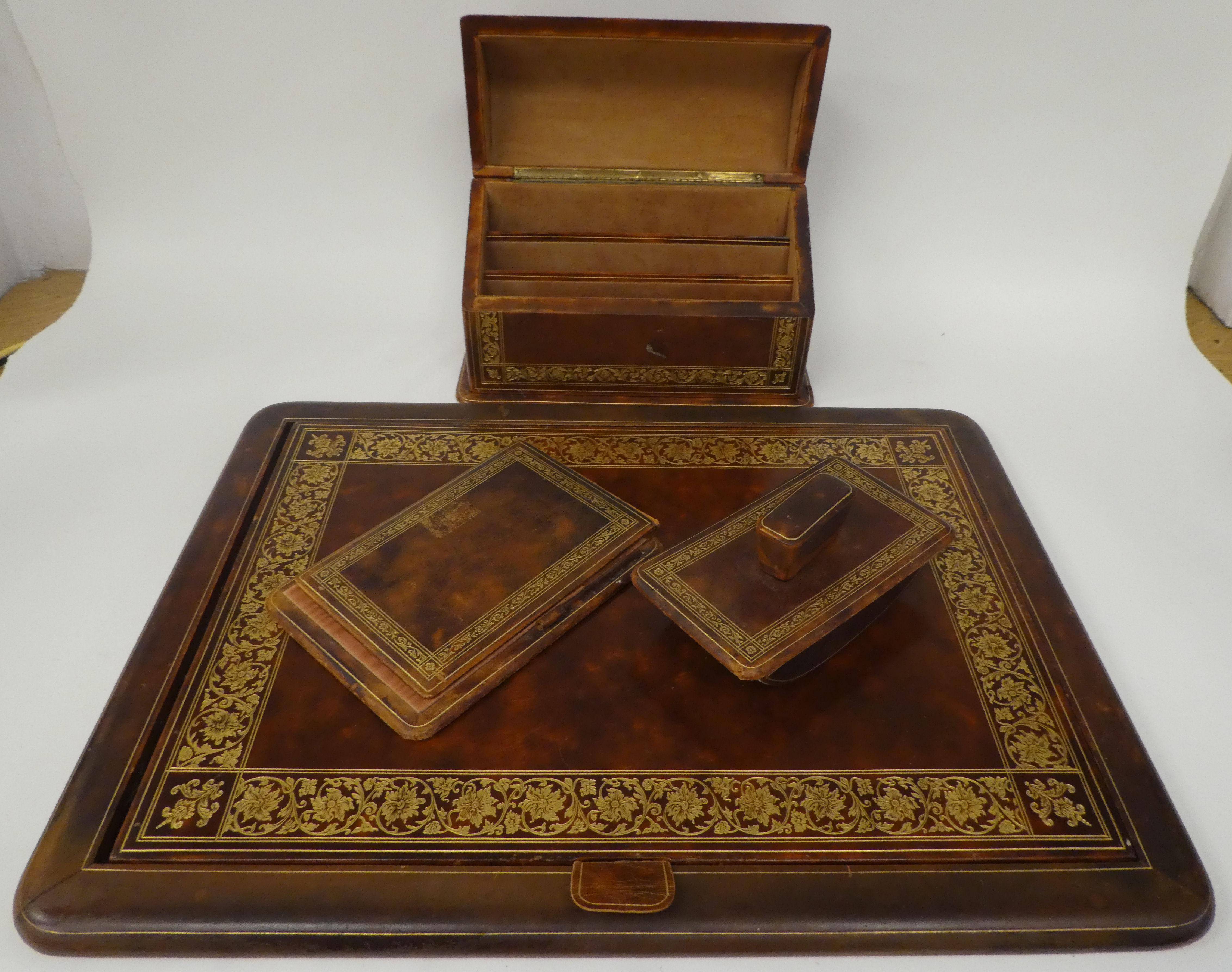 A Liberty gilded and burnished brown hide covered desk set, comprising a two-part blotter  19" x
