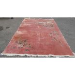 A Chinese washed woollen rug, decorated with flora, on a salmon pink coloured ground  100" x 148"