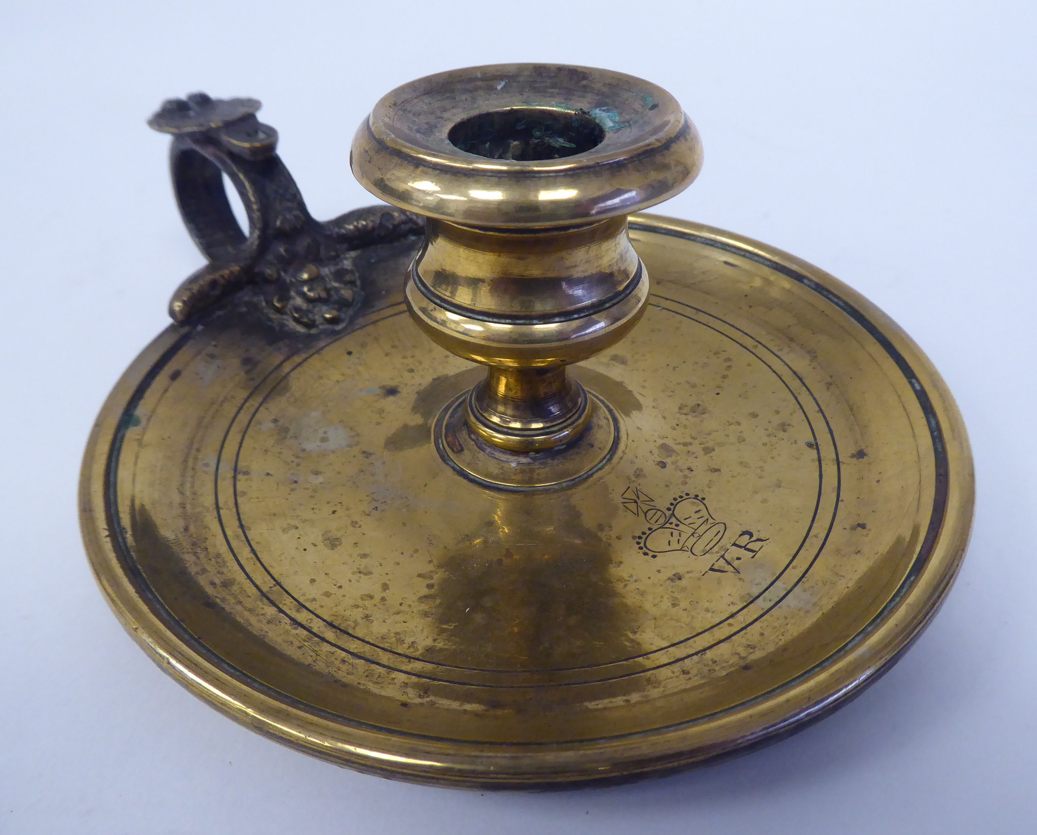 A Victorian brass chamberstick with a coiled snake handle and shell cast tab  bears a Queen Victoria