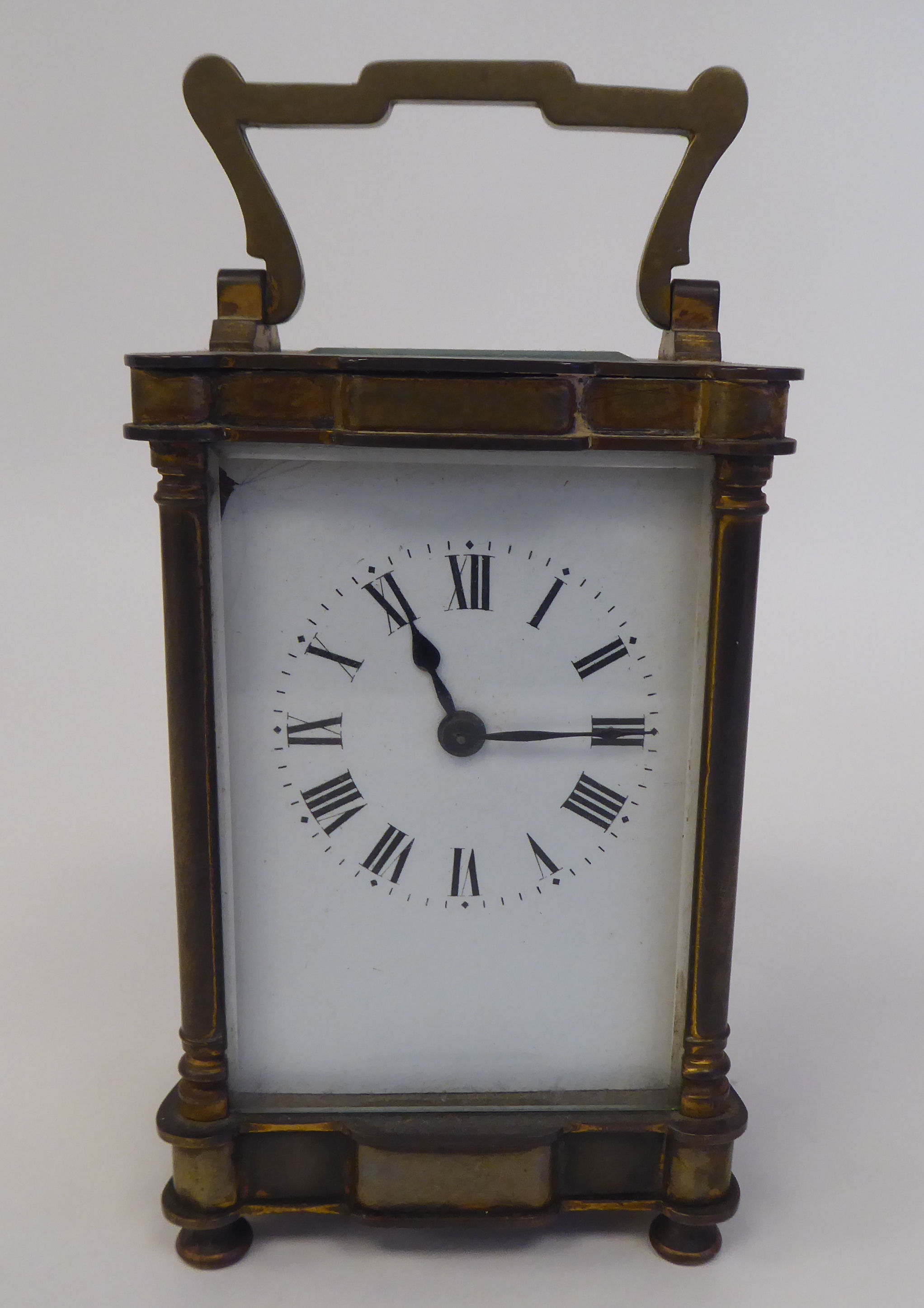 A 1920s lacquered brass cased carriage timepiece with bevelled glass panels and a folding top