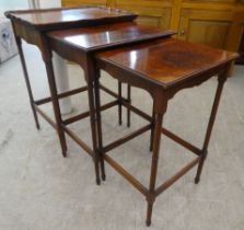 A nesting set of three mid 20thC burr walnut finished occasional tables, raised on turned, slender