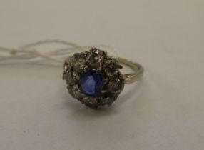 A (probably) platinum claw set, floral design diamond and single sapphire set cluster ring